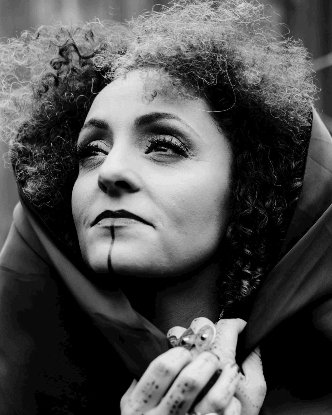 Anissa Lalahoum, en noir et blanc, une capuche sur les cheveux, le regard levé vers la gauche.