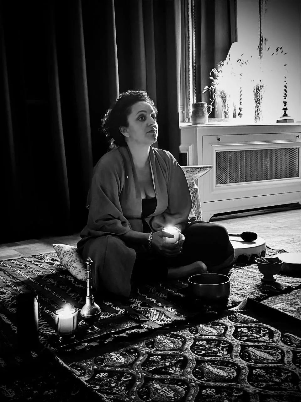 Anissa Lalahoum assise en tailleur sur un tapis, une bougie allumée entre les mains.